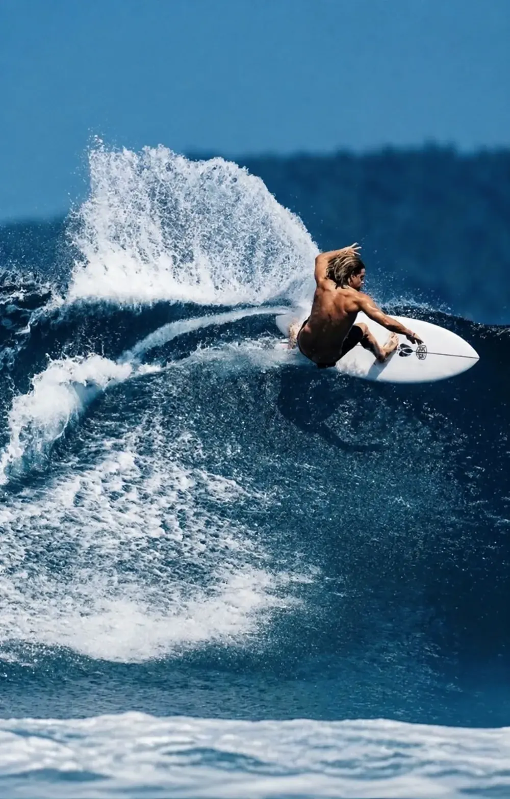 Surfer carving across a blue wave