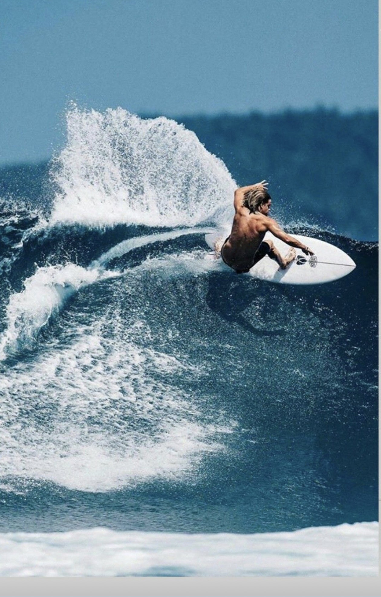 Surfer carving across a blue wave